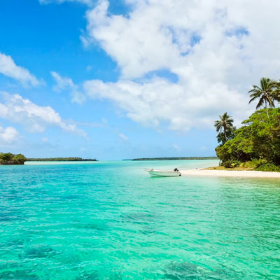 Photograph of a boat in water off of tropical beach